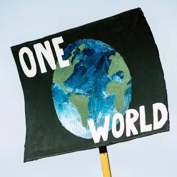 A sign with the words one world painted on it.