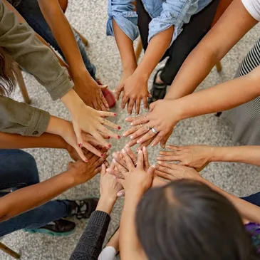 A group of people holding hands in the middle of a circle.